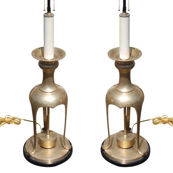 A pair of large brass table lamps in the manner of James Mont. Tripod form with round black bases.