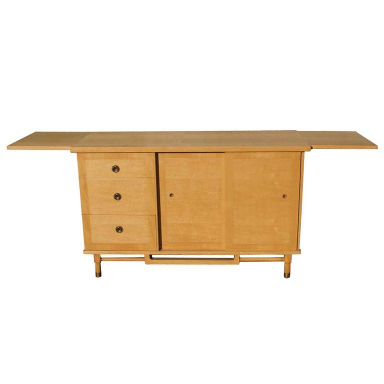 A Mid-Century Modern sideboard/buffet designed in the style of Milo Baughman. Two sliding doors revealing two storage areas and a drawer. Three drawers with brass pulls. Two 15