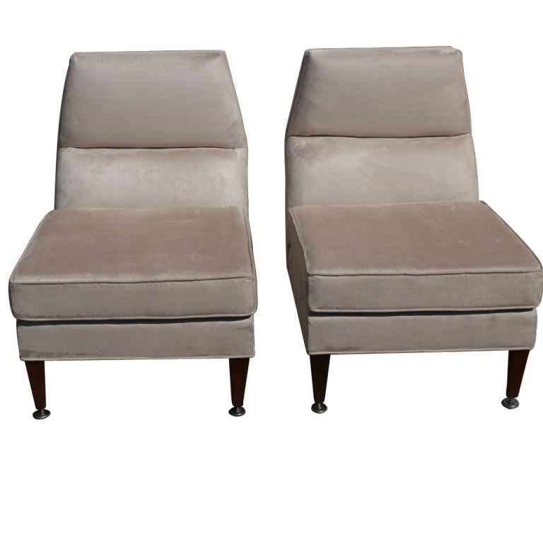 A Mid-Century Modern pair of lounge chairs. Newly upholstered in a tan or gray ultrasuede with tapering wooden legs.