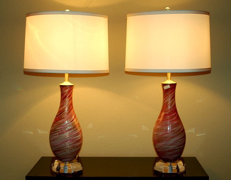 A very stylish and elegant pair of Seguso Murano lamps from the 1950s, swirled in RASPBERRY AND CRIMSON and heavily dusted with GOLD. The lamps are mounted on Lucite chunks. 

The lamps are 28 inches from tabletop to socket top.  As shown, the top