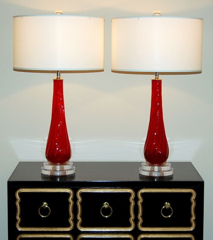 These vintage lamps are a vibrant RUBY RED, extremely rare for Murano glass.  They are ribbed in a diagonal pattern, mounted on a two-stepped Lucite base.

The lamps are 24 inches from table top to socket top.  As shown, the top of shade is 31