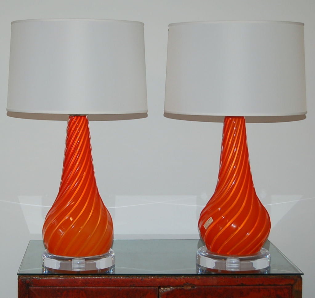 Heavily ribbed vintage Murano lamps in PERSIMMON ORANGE. A perfect pair, ready to light up the room.

They stand 26 inches from tabletop to socket top. As shown, the top of shade is 28 inches high. Lampshades are for display only and not available