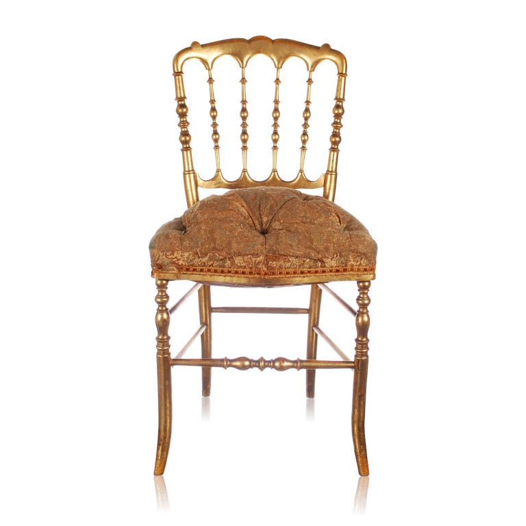 This is a splendid pair of antique Chiavari wood chairs with original gold leaf finish. These are NOT the brass chairs so commonly found, these are the real ones made of wood and beautifully carved and shaped. The upholstery may be original and