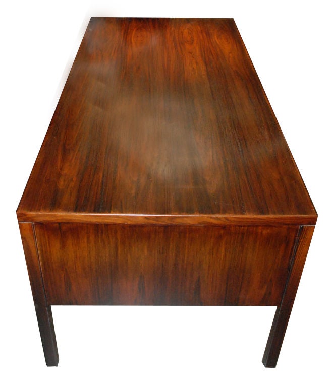 Omann Junior mid-century modern desk with six drawers, front with open shelf between two locking compartments, sitting on tapered legs.