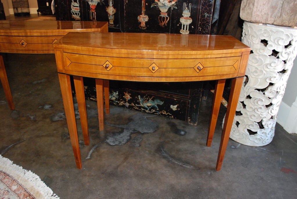 A pair of Danish bow front console tables, fronts and tapered legs with line inlay, one long drawer each.
