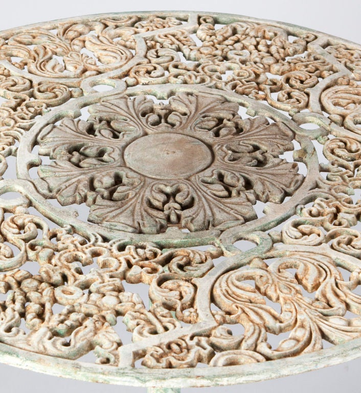 A round cast iron Garden Table from Provence with intricate carvings on top. Table has traces of a previous green paint and rust spots for more character.