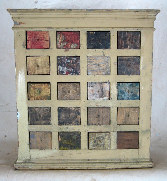 Hanging cabinet for storage of different colored pigment for use by artist. Each drawer had the color inside painted on the outside, scrapped off then repainted numerous times, resulting in a work of art itself.