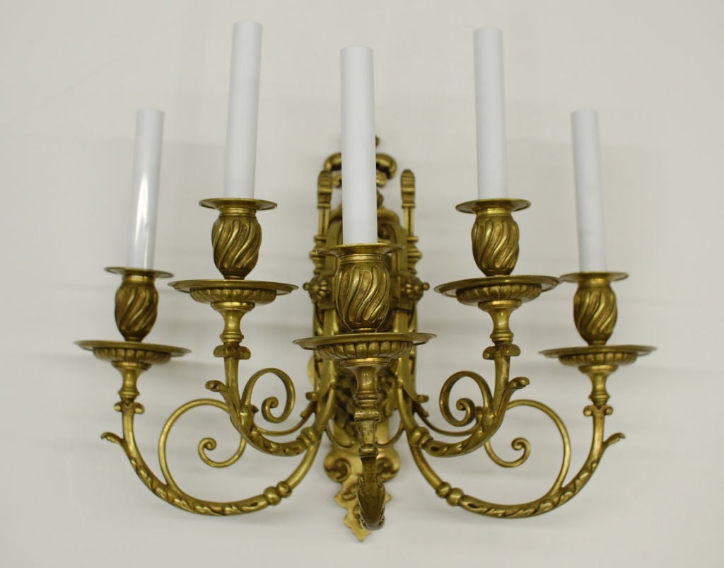 Pair of 5 arm sconces with scroll detail on the arms at 2 levels (3+2). Ornamental backplate. Rubbed antique brass finish.