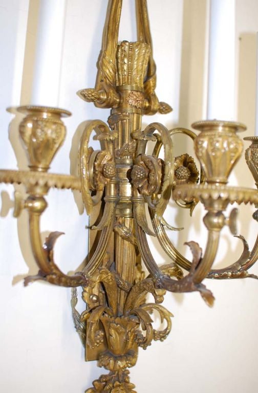 Pair of exquisitely detailed sconces with handchaised brass cast work. The ribbon & bow theme is combined with quiver of arrows terminating with a tassel.