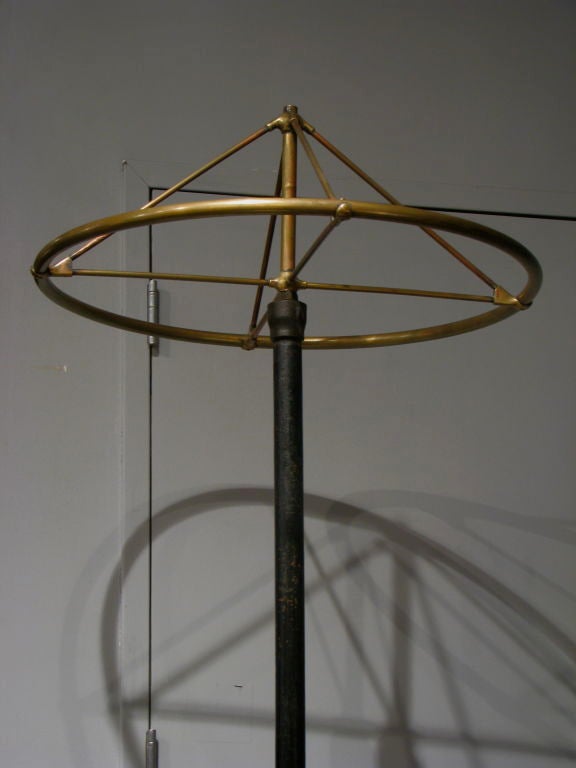 Massive Cast iron and brass circular coat rack on caster wheels<br />
Early industrial American retail fixture from a mens haberdashery in Boston.