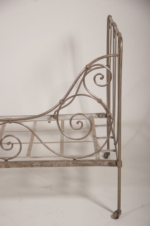 A French Mid. 19th Century Hand Forged Iron Daybed with scrolling design and raised on castors.