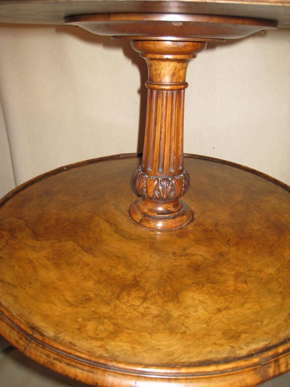 Victorian two-tier figured walnut dumb waiter on tripod base over shell form feet; the central column fluted over acanthus base. The larger tray is 24