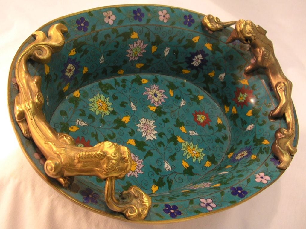 Blue and floral cloisonné and gilt bronze footed bowl with  gilt bronze dragon form handles and banding top and bottom, raised on four lotus design feet.