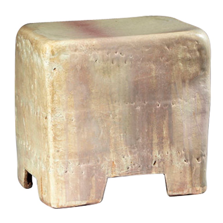 Ceramic stool in a pale colored glaze with a red band.
