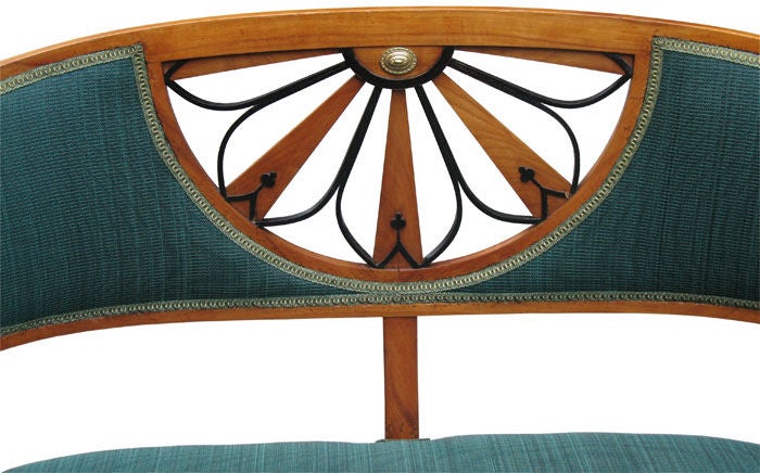 Small finely detailed Viennese Biedermeier barrel back settee in cherry wood on pine. Channeled rail on corresponding tapered legs in straight and saber shape. Seat-back with radial pierced fan motif, partly ebonized. Original brass rosette. Padded