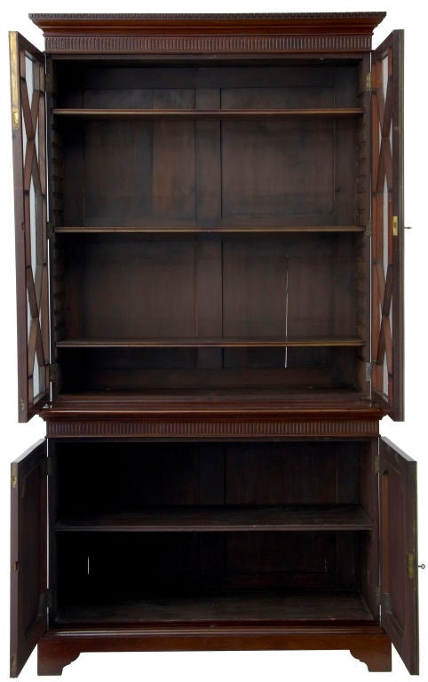 A 19th century mahogany bookcase with astragal glass two-door cabinet on two door cupboard base fitted with shelves and standing on bracket feet, circa 1830.