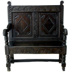 A 17th Century style carved oak panel back oak settle