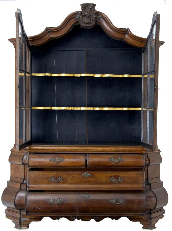 18th Century dutch oak vitrine on bombe base circa 1780.  The double Bombay base fitted with two short drawers over two long drawers all fitted with original brass handles and escutchions.  The cabinet is fitted with shaped shelves.