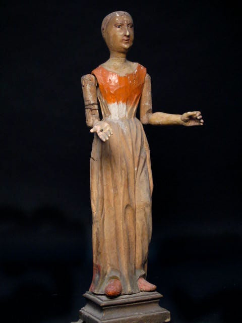 Santos, hand carved wood dress, detailed face with touch of orange on chest, articulating arms and glass eyes.