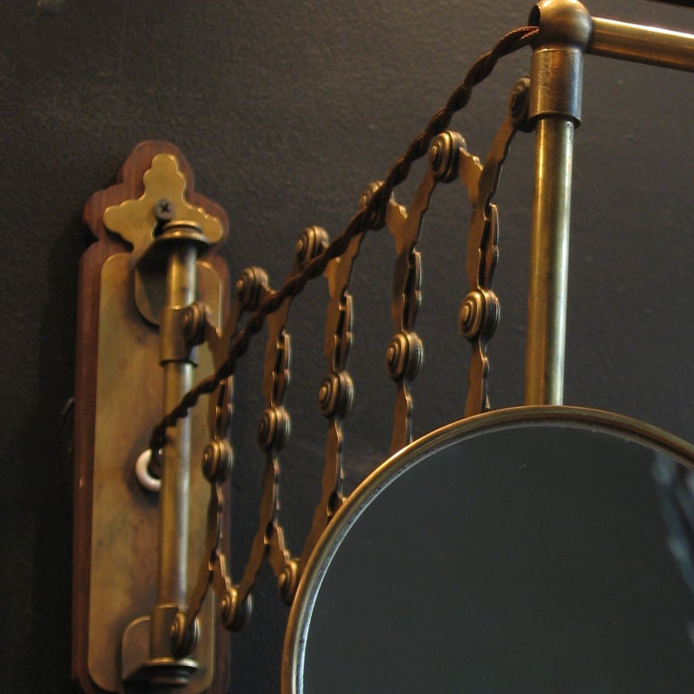 Unusual brass wall mount light fixture with scissor arm, and mirror.