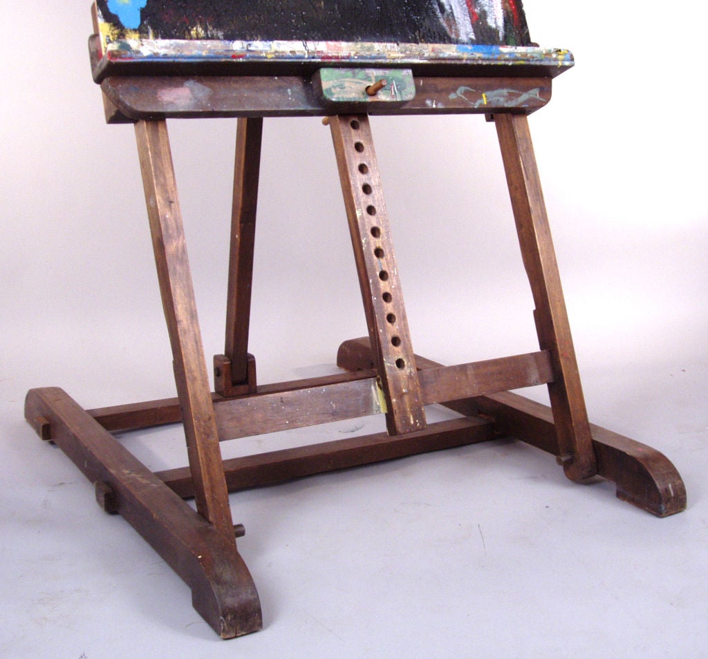 a wonderful vintage painter's easel, with adjustmets for height and angle of the easel. designed to support even a very large canvas, it also has a charming bench for holding paints and brushes, that is notched to fit around the upright center stem.