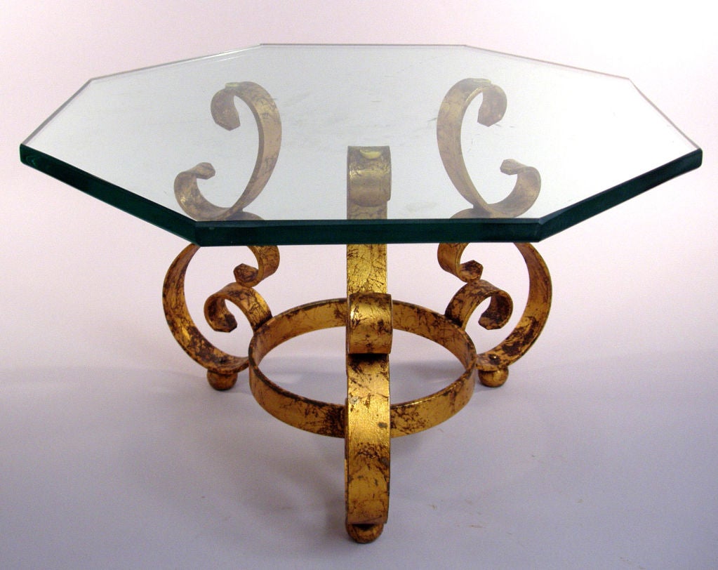 a charming pair of gold leaf scroll tables with thick octagonal glass tops. nice design perfect for lamp or bedside tables. heavy and very well made.