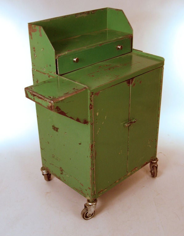 a very charming small vintage industrial rolling cabinet. fitted with a drawer on top as well as a series of drawers in the interior. retains it's original painted distressed apple green finish.