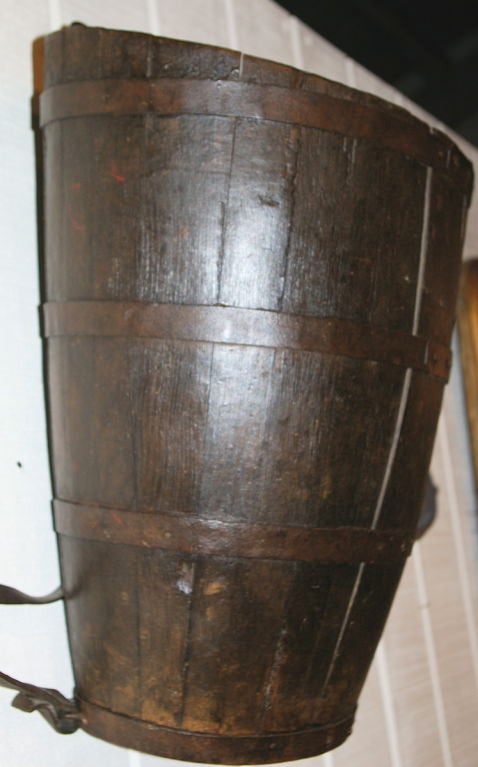 This type of basket used in the vineyards was carried on the shoulder via leather straps on the back.  It is made of oak and banded in iron. The oak has a remnant of an old varnish finish. It originates from the Burgundy Cote d'Or wine region.