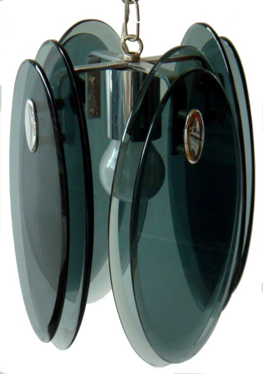 Early Mid-Century Modern Italian beveled thick glass and chrome pendant light fixture by Fontana Arte from the 1960s.
The fixture has eight thick beveled smoked glass panels, two on each side, with polished chrome concave details in the middle of