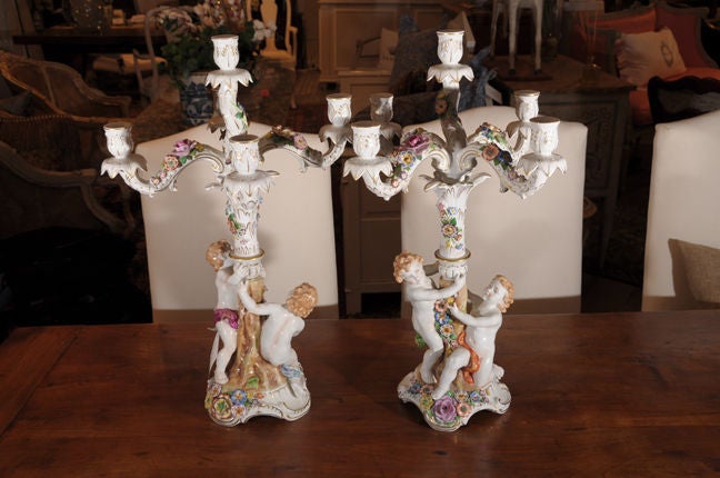 White w/ gold articulation with colorful painted flowers w/ two putti holding the base, von Schierholz.