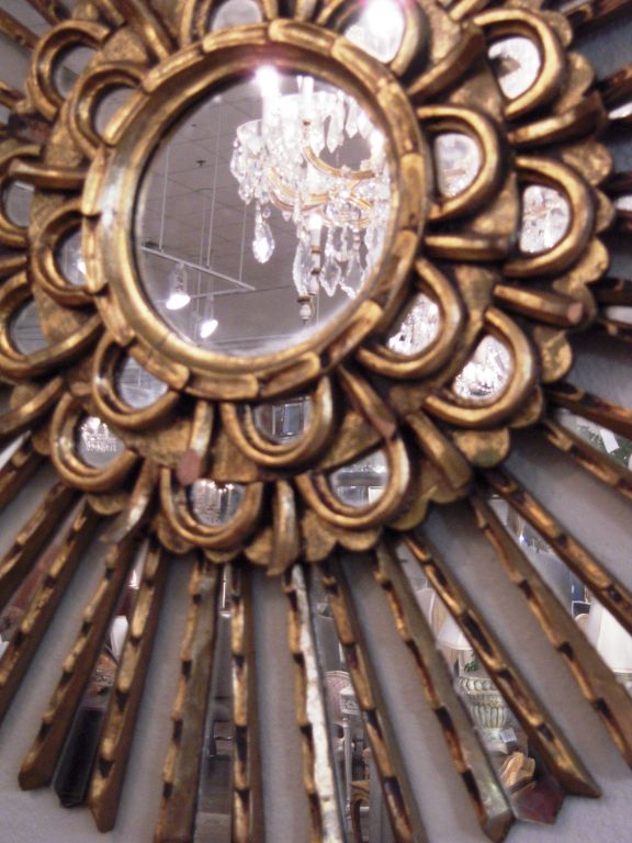 Large carved wood Sun Burst Mirror. Each small mirrored piece is surrounded by gilt carved wood with fine detail.Impressive both in size and and glamour