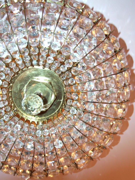 This decorative ceiling light fixture features a metal framework with graduated-sized crystals. The crystals are clear. (The pink color in these photos is because of the ceiling color in our store.)