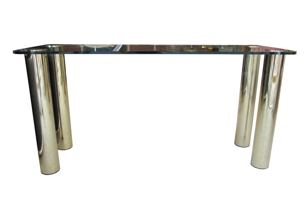 USA,
circa 1970s.
Four heavy brass-plated legs support and pierce the top, surmounted by cast brass caps. Radiused corner rectangular glass top 5/8