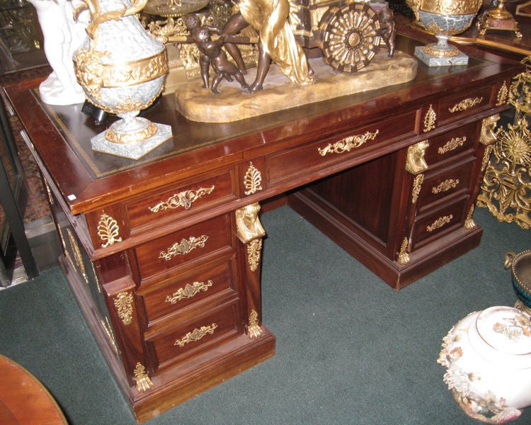 This mahogany desk in the French Empire style features extensive gilt bronze mounts on every face. Its craftsmanship is very high, comparable to works by Maison Krieger. The drawers have hand-cut dovetails, we have the original key and the locks are