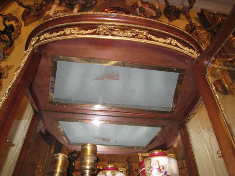 This lovely vitrine by Francois Linke (1855-1946) on cabriole legs has a serpentine shape, rouge marble top and extensive gilt bronze mounts including swags, cherubs, and female masks at the corners. It is distinguished for its three Vernis Martin