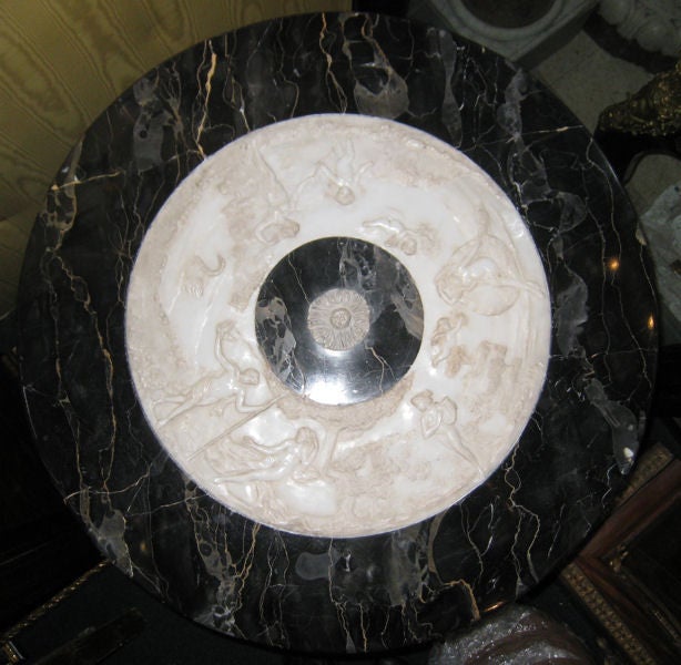 This lovely Italian marble center table features neoclassical carved figures in a ring around the center and a variegated black/grey marble-top. The pedestal features carved grape bunches, acanthus leaves and animal claw feet resting upon a
