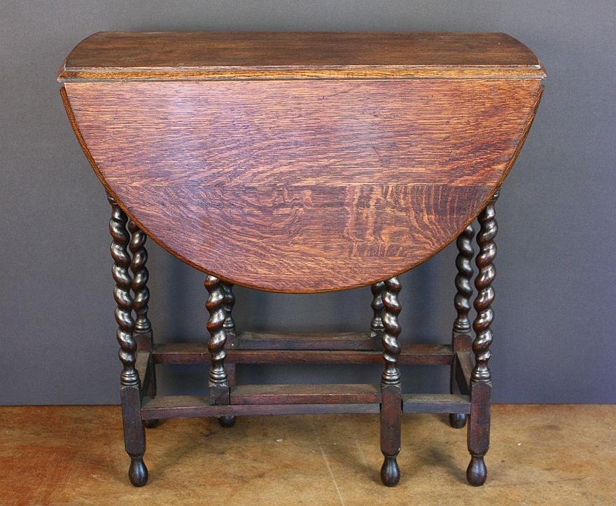 An English drop-leaf table of oak featuring an oval moulded top over turned barley-twist gateleg supports.<br />
<br />
H 29 1/2 x W 29 3/4 x D 14 1/2 (Each leaf 14