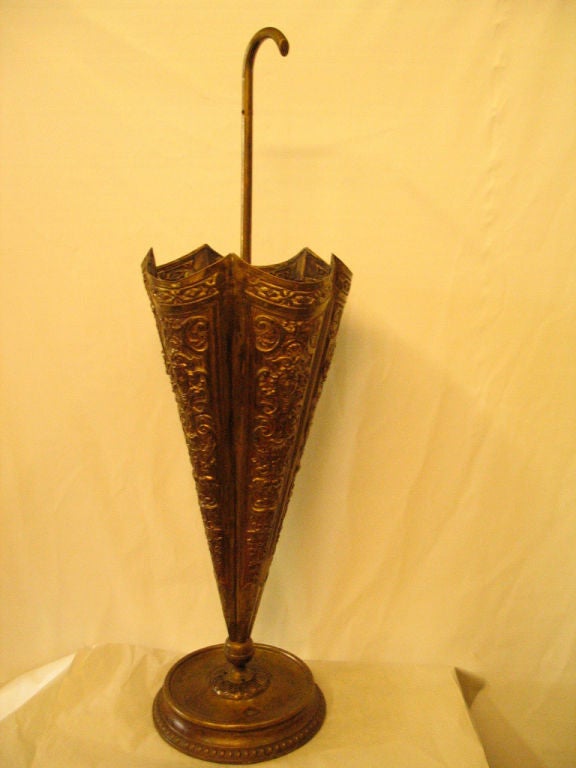 A vintage umbrella/parasol holder is, itself, designed in the shape of a decorative<br />
umbrella standing, partially open, upside down mounted on a decorated base. The<br />
umbrella 