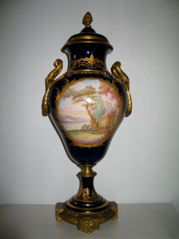 An outstanding Sevres cobalt blue porcelain 19th century palace urn. Gold accents and beautiful bronze decorations, notably applied fanciful bronze handles, add elegance to this stately palatial urn. The hand painted front panel depicts the goddess
