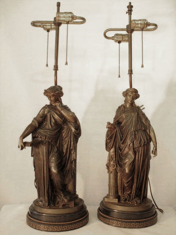 Superbly sculpted bronzes stand serenely atop an oval platform of black marble trimmed with a Greek key motif. Drama in decoration is achieved by this artist and<br />
attention to detail is apparent in these exceptional lighting devices. The