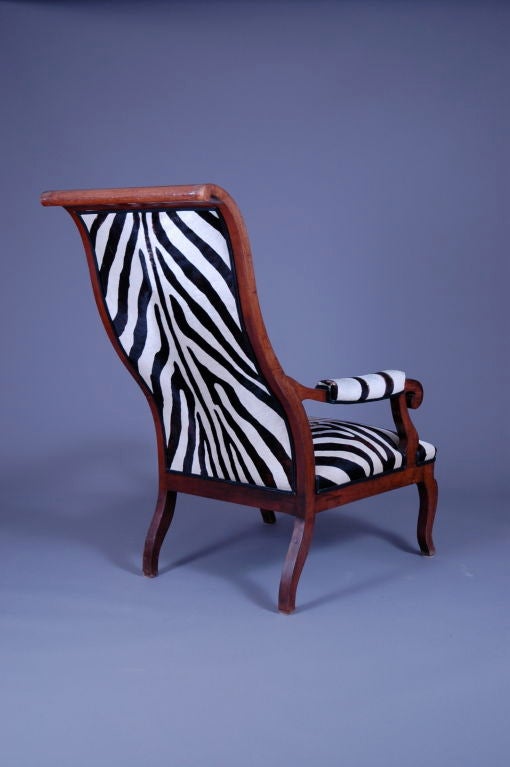 Stylish and comfortable high back arm chair. The swayed back was designed to accompany the large hats worn by society ladies in the late 19th century.<br />
Covered in a faux zebra