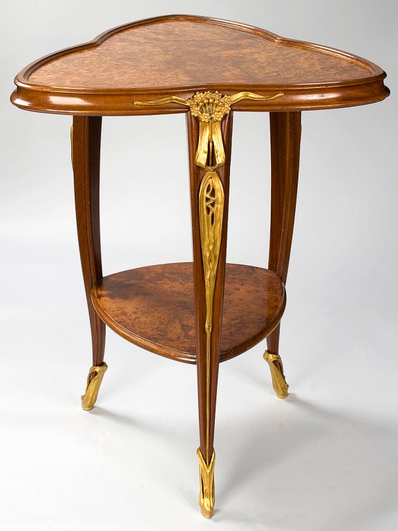 A French Art Nouveau table by Louis Majorelle in carved mahogany and bird’s eye maple with parcel gilt floral details.