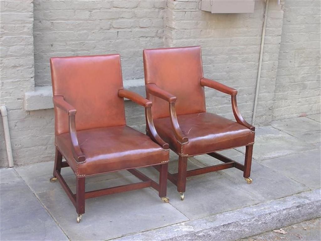 Pair of English Chippendale mahogany gainsborough leather arm chairs with original brass casters.