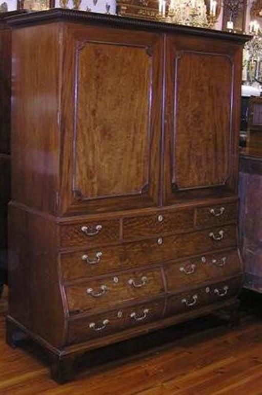 English Chippendale Mahogany bombay linen press with carved dental molding, flanking book matched molded edge doors, fitted interior adjustable shelving and lower drawers, original gilt brasses, and terminating on original ogee bracket feet. Late