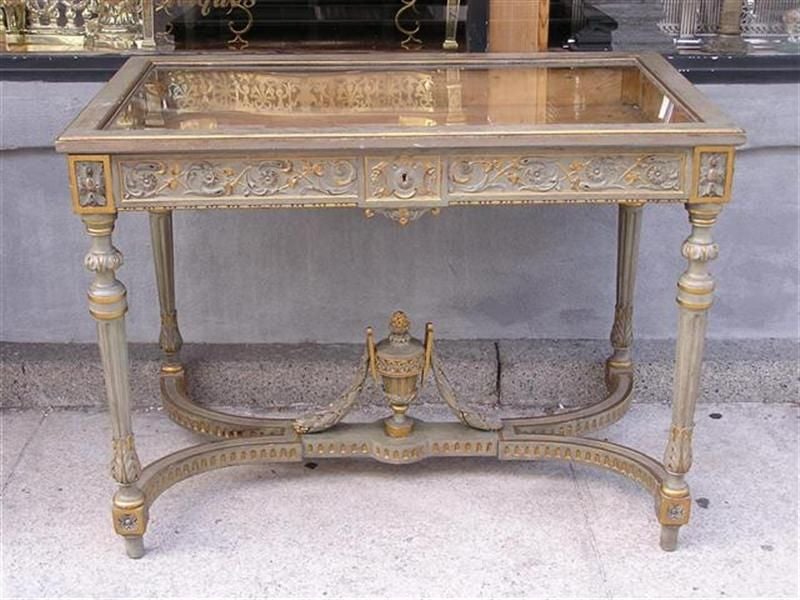 Pair of Italian painted and gilt vitrines with hinged glass tops, carved intertwined decorative floral vine motif, corner floral medallions, and terminating on bulbous fluted legs supported by connecting cross stretchers with gilt centered
