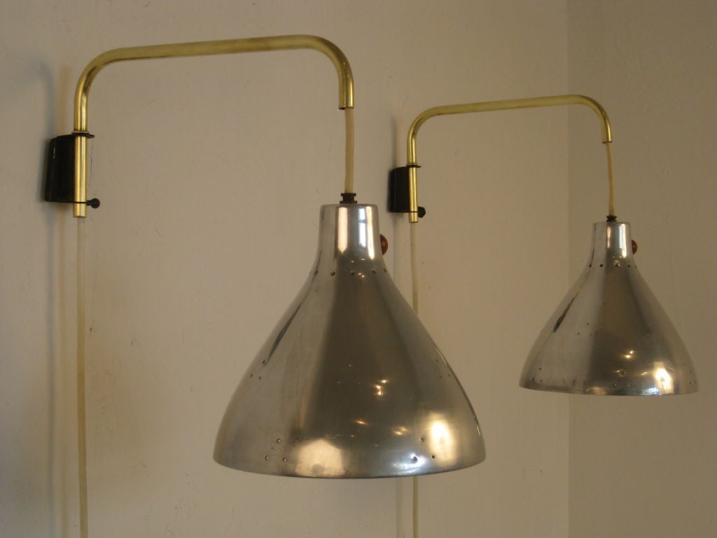 Pair of brass arm sconces with pierced aluminum shades by Koch Lowy. Switch has a turned wood ball knob. There is a counter balance weight which allows you to adjust the shade to any height needed. The shade is 8 3/4