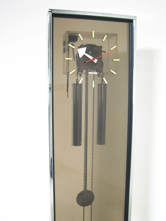 Elegant floor clock in chromed steel and smoked Lucite, designed by George Nelson for Howard Miller, ca. 1960s.    Melodious chimes on the hour and half-hour.   Iconic Nelson clock hands.
