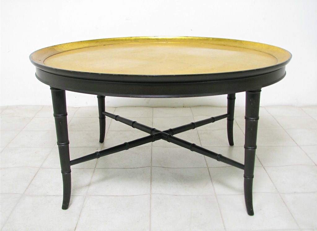 Gilt cocktail coffee table by Kittinger Furniture, ca. 1950s.  Richly gilded gold leaf top on ebonized faux bamboo base with cross stretchers.