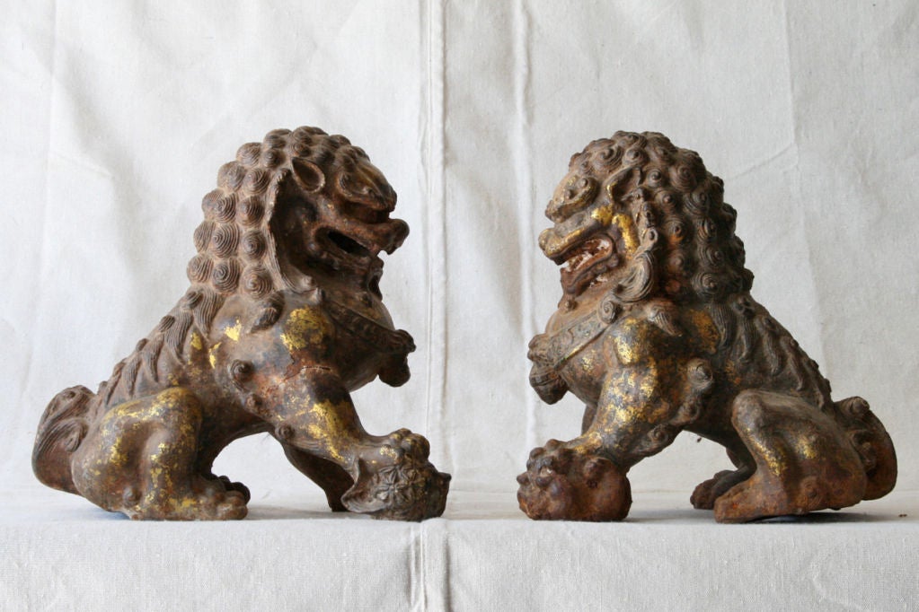 A wonderful pair of Chinese cast iron foo dogs retaining traces of original gilt decoration.