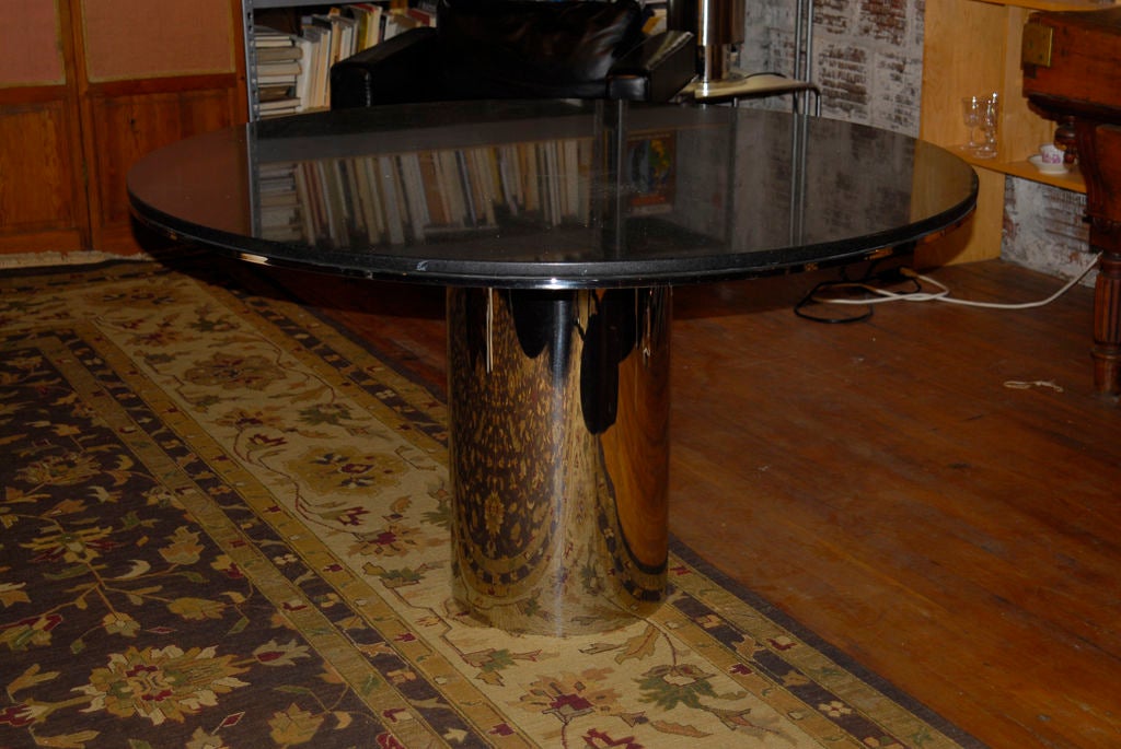 A sleek polished stainless steel and black granite pedestal table made for Brueton- 
